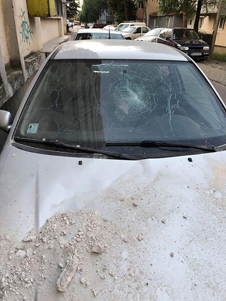 Mașina avariată de tencuiala căzută de pe bloc în bucăți mari