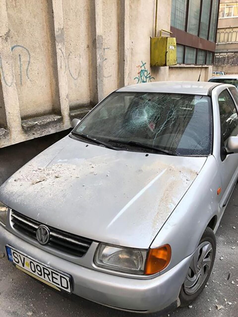 Mașina avariată de tencuiala căzută de pe bloc în bucăți mari