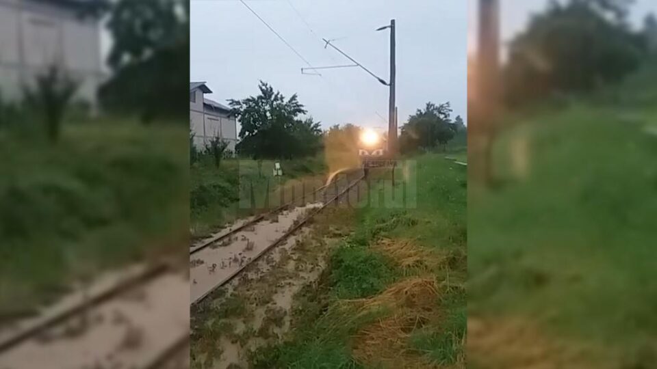 Tren cu călători, blocat de apă și aluviuni