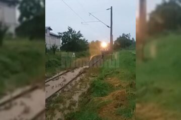 Tren cu călători, blocat de apă și aluviuni
