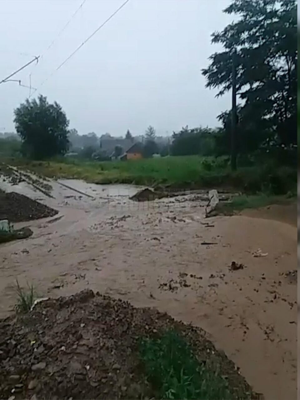 Tren cu călători, blocat de apă și aluviuni