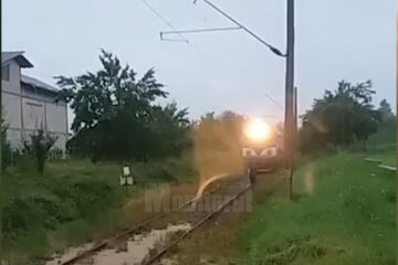 Tren cu călători, blocat de apă și aluviuni