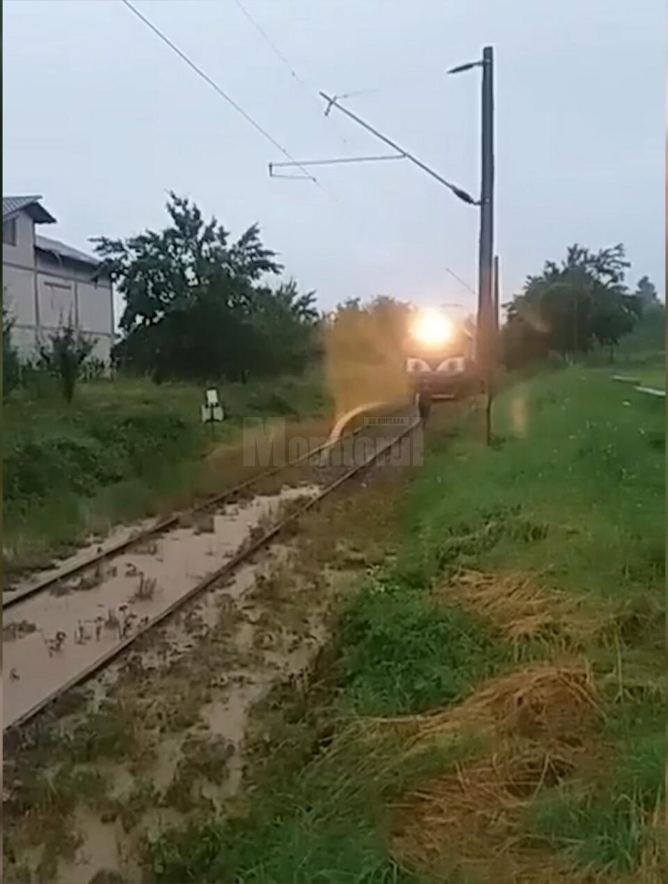 Tren cu călători, blocat de apă și aluviuni