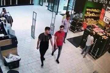 Doi tineri îmbrăcați bine intră în magazin relaxați și apoi se opresc la raionul auto