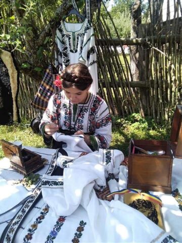 O tânără din Cajvana, Diana Seserman, coase cămăși, curele și chimire cu mărgele