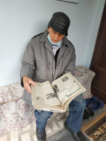 Sevastian Bogus răsfoind o colecție de ziare mai vechi