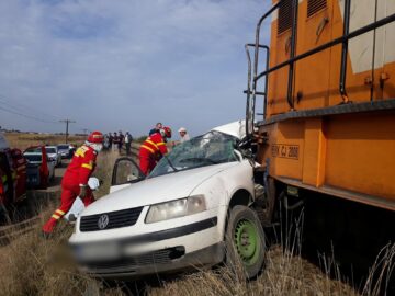 Mașina a fost lovită în plin de un tren la o trecere la nivel aflată în câmp