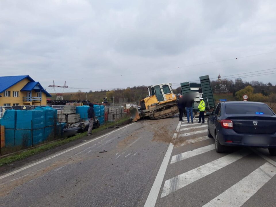 Utilaj căzut de pe o platformă, peste două autoturisme, în trafic