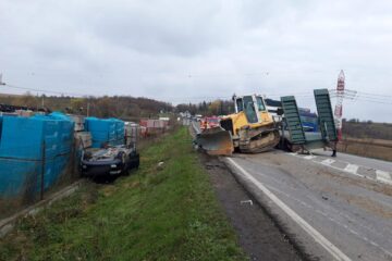 Utilaj căzut de pe o platformă, peste două autoturisme, în trafic