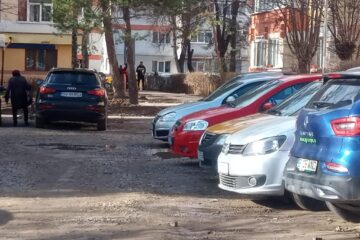 Un teren mocirlit, ocupat de mașini, „spațiul verde” din zona Pieței George Enescu, pentru care s-a luat decizia care permite amenajarea sa ca parcare de reședință