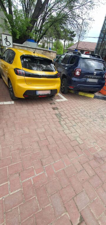 Mașină parcată pe locuri cu handicap și mașină parcată pe trotuar în parcarea Primăriei Suceava