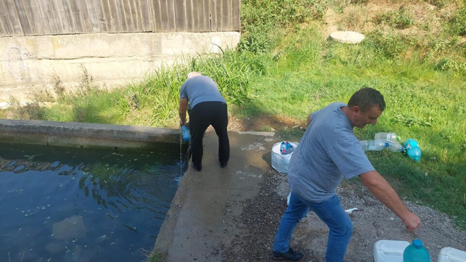 Localnicii cară apa cu canistre și bidoane, pe care le încarcă în portbagaj