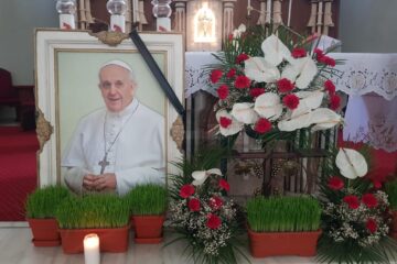 Imaginea Papei Francisc cu o panglică neagră și o candelă aprinsă, lângă lumânarea pascală, în Biserica Romano-Catolică din municipiul Suceava