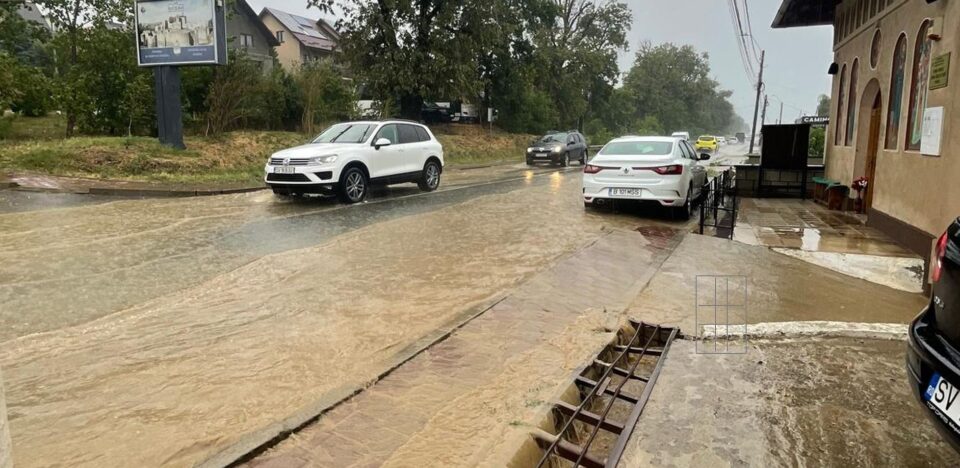 Apa de ploaie se adună pe stradă și se revarsă spre biserică și în curtea casei preoților Hirghiligiu